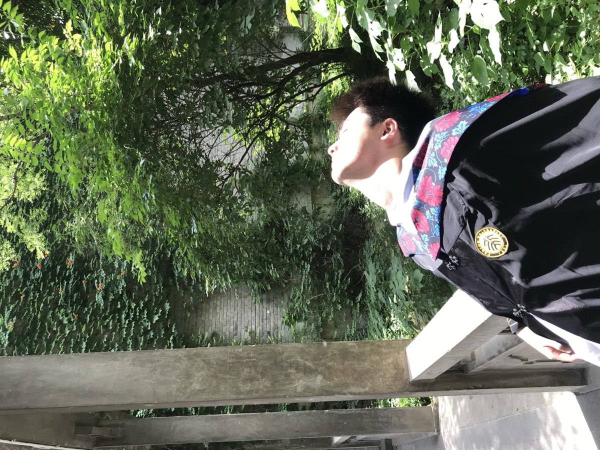 Kuangzhi Ge in a sunlit green courtyard after graduating from Peking University